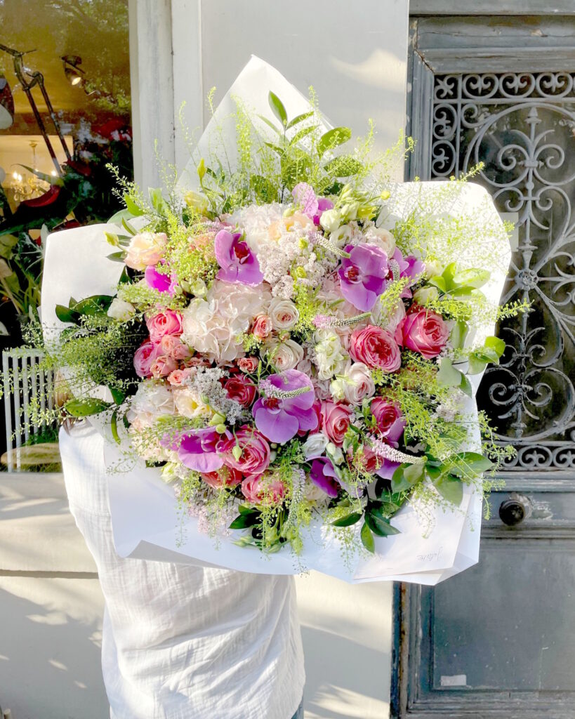 Très grand bouquet dans des couleurs tendres : blanc, rose et parme, avec orchidées, hortensias, roses, thlaspi et autres fleurs champêtres.